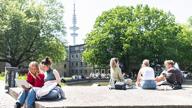 Studierende sitzen am Uni Wasserspiel