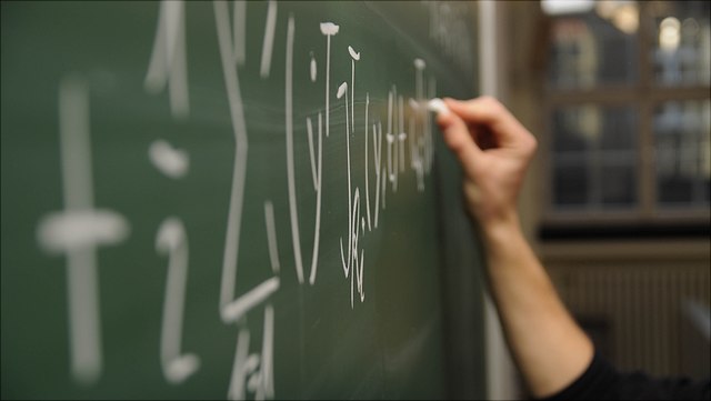 Person schreibt an die Tafel