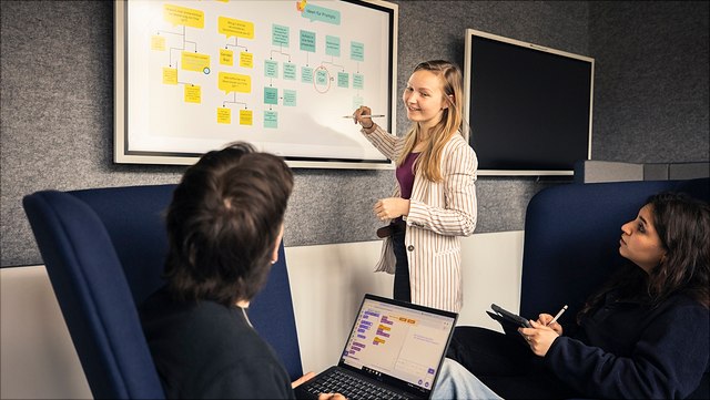 Drei Studierende beraten sich vor einem digitalen Board