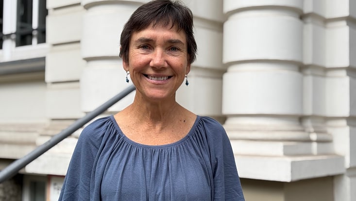 Dame in blauer Bluse vor Haus